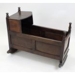 A oak cradle, 18th century and later, with flat canopied hood and turned finials to the corners,