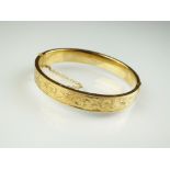 A 9ct gold hinged bangle, with engraved bright cut decoration, weight 16.