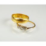 A 22ct gold wedding band, ring size K 1/2, together with a graduated three stone diamond ring,