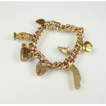 A yellow metal hollow curb link bracelet, with attached charms,