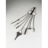 A late 19th century white metal chatelaine, suspending seven white metal and silver implements,