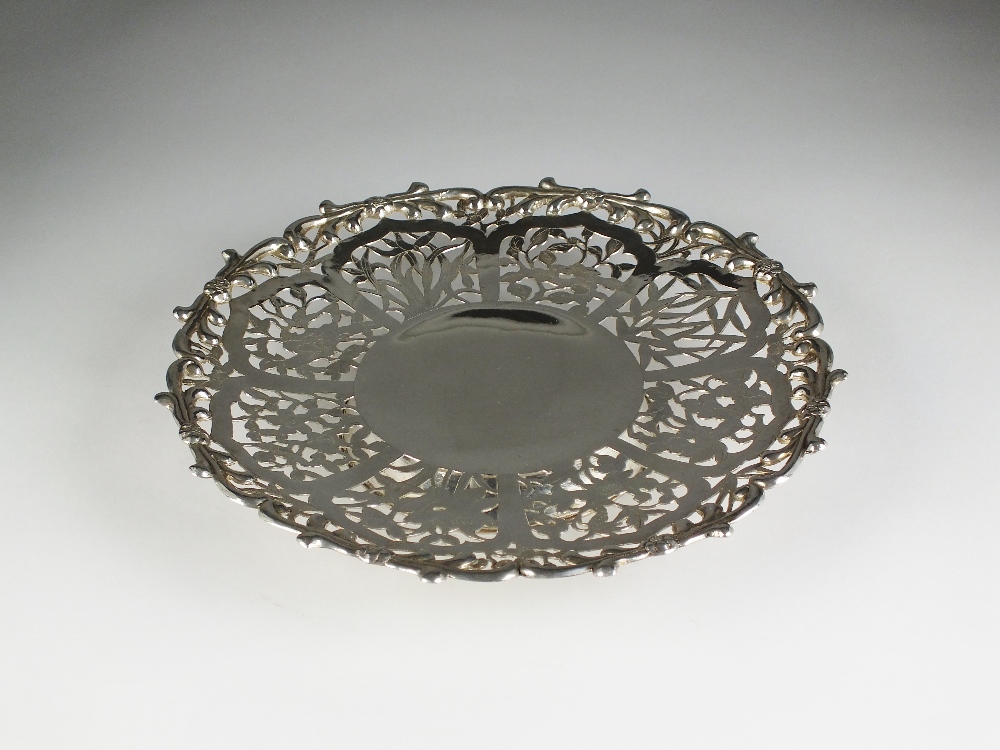 A white metal pierced shallow dish, with bamboo and blossom decoration, raised on collet foot,