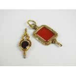 A faceted garnet and stone set swivel watch key, set in decorative scrolling yellow metal mount,