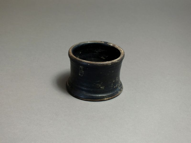 Greek, ceramic black glazed phyxis, 5th century BC; rounded rim, short body with flared base ring.