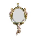 A German porcelain overmantel mirror, late 19th century, the oval mirror flanked by two putti, a