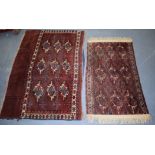 A PERSIAN RED GROUND SADDLE RUG, together with another similar. Largest 105 cm x 70 cm.