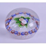 AN ANTIQUE GLASS PAPERWEIGHT decorated with a central floral motif, encased by white ribbon twist