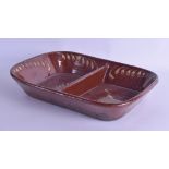 AN ANTIQUE TREACLE DRIP GLAZED COUNTRY POTTERY SERVING DISH painted with swirling motifs. 33 cm x 27