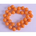 AN EARLY 20TH CENTURY CARVED ORANGE HONEY AMBER NECKLACE. 38 grams. 42 cm long.