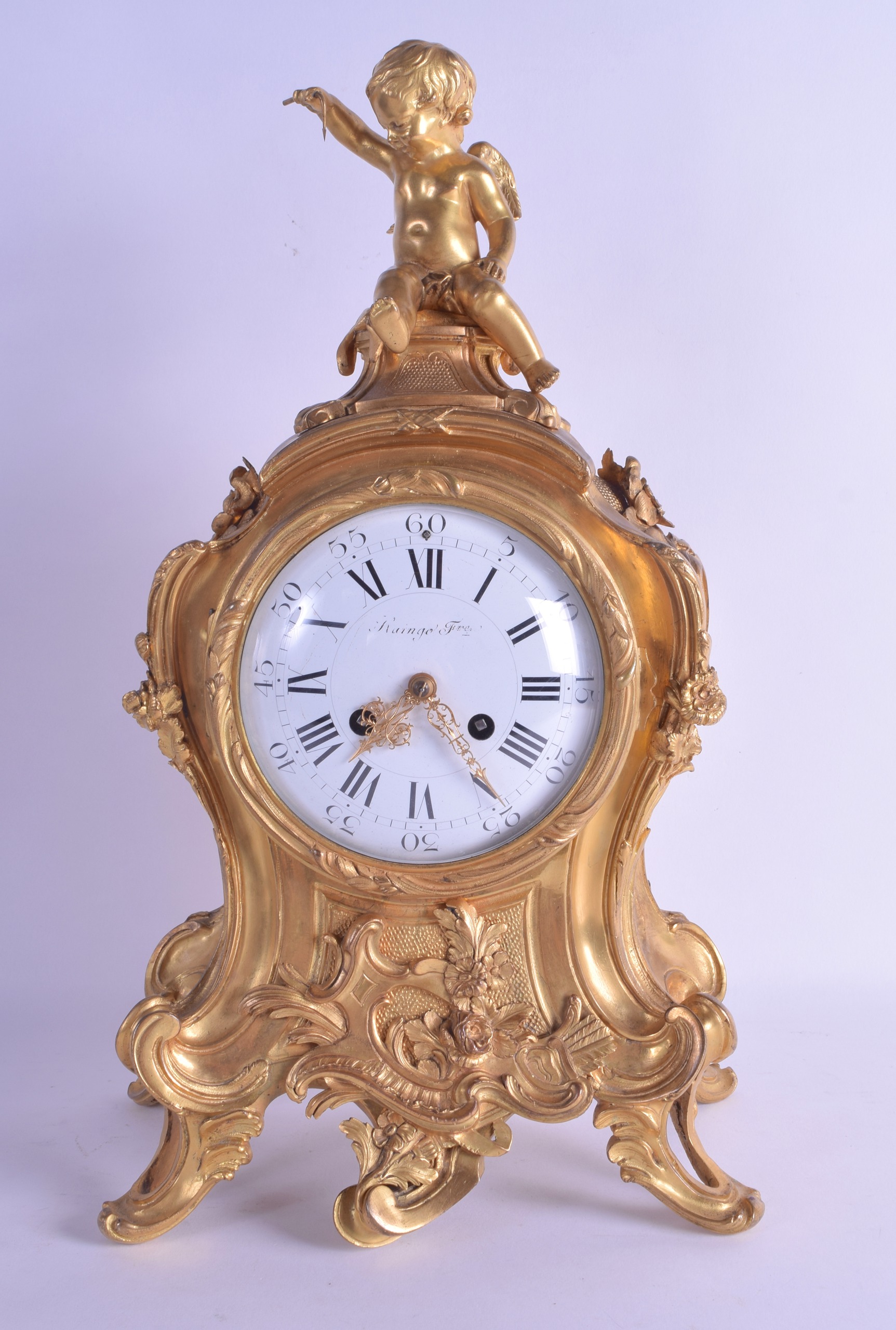 A MID 19TH CENTURY FRENCH ORMOLU ROCOCO MANTEL CLOCK modelled with a seated cupid upon a scrolling