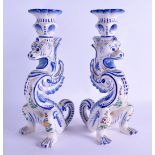 AN UNUSUAL PAIR OF FRENCH FAIENCE POTTERY CANDLESTICKS in the form of stylised beasts painted with