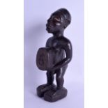 AN AFRICAN TRIBAL CARVED AND LACQUERED WOODFETISH FIGURE modelled standing and holding his