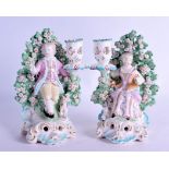 18th c. Derby pair of candlestick figure of a boy and girl seated before a brocage holding a flower.