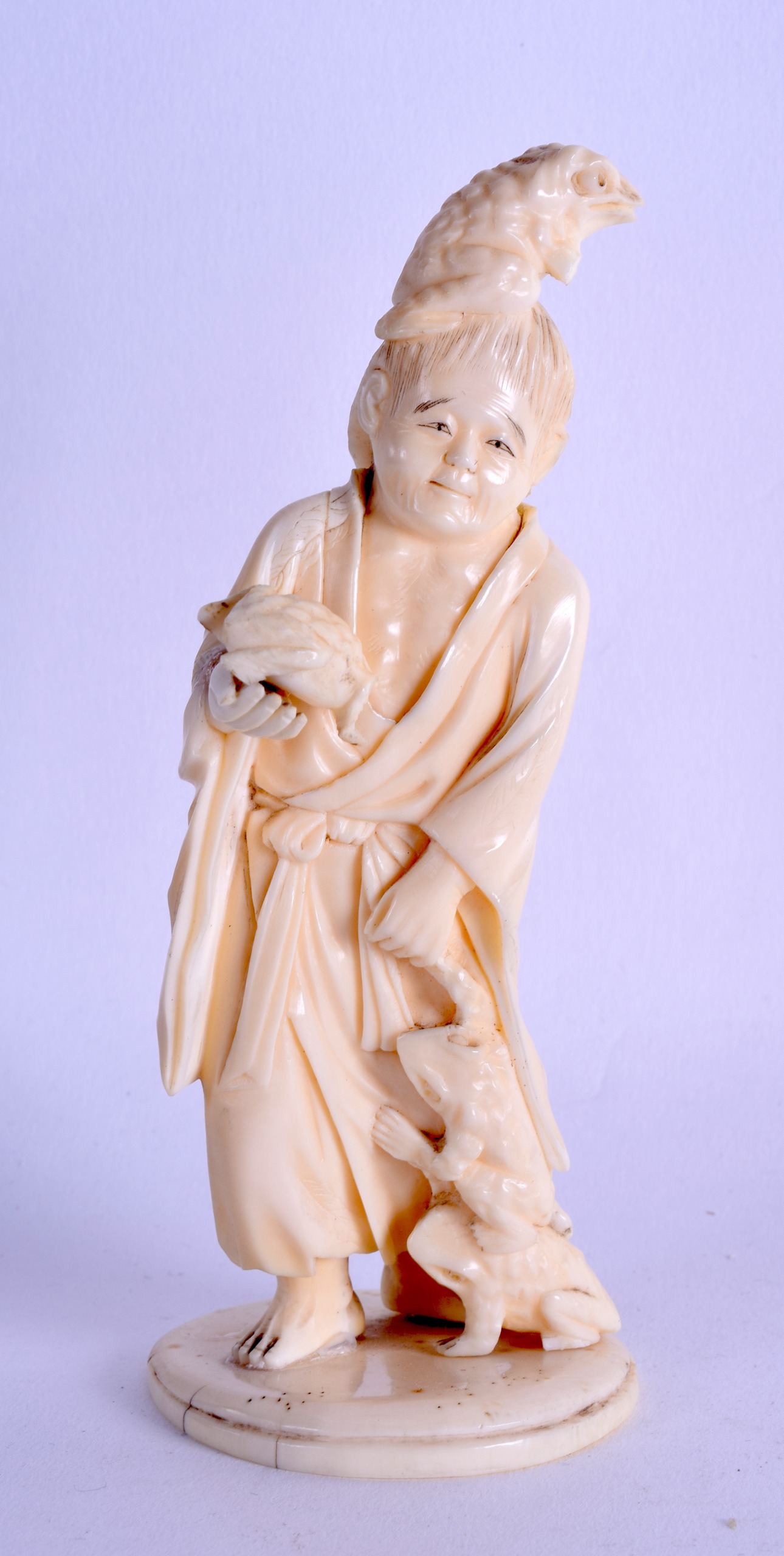 A LATE 19TH CENTURY JAPANESE MEIJI PERIOD CARVED IVORY OKIMONO modelled as a male holding toads.