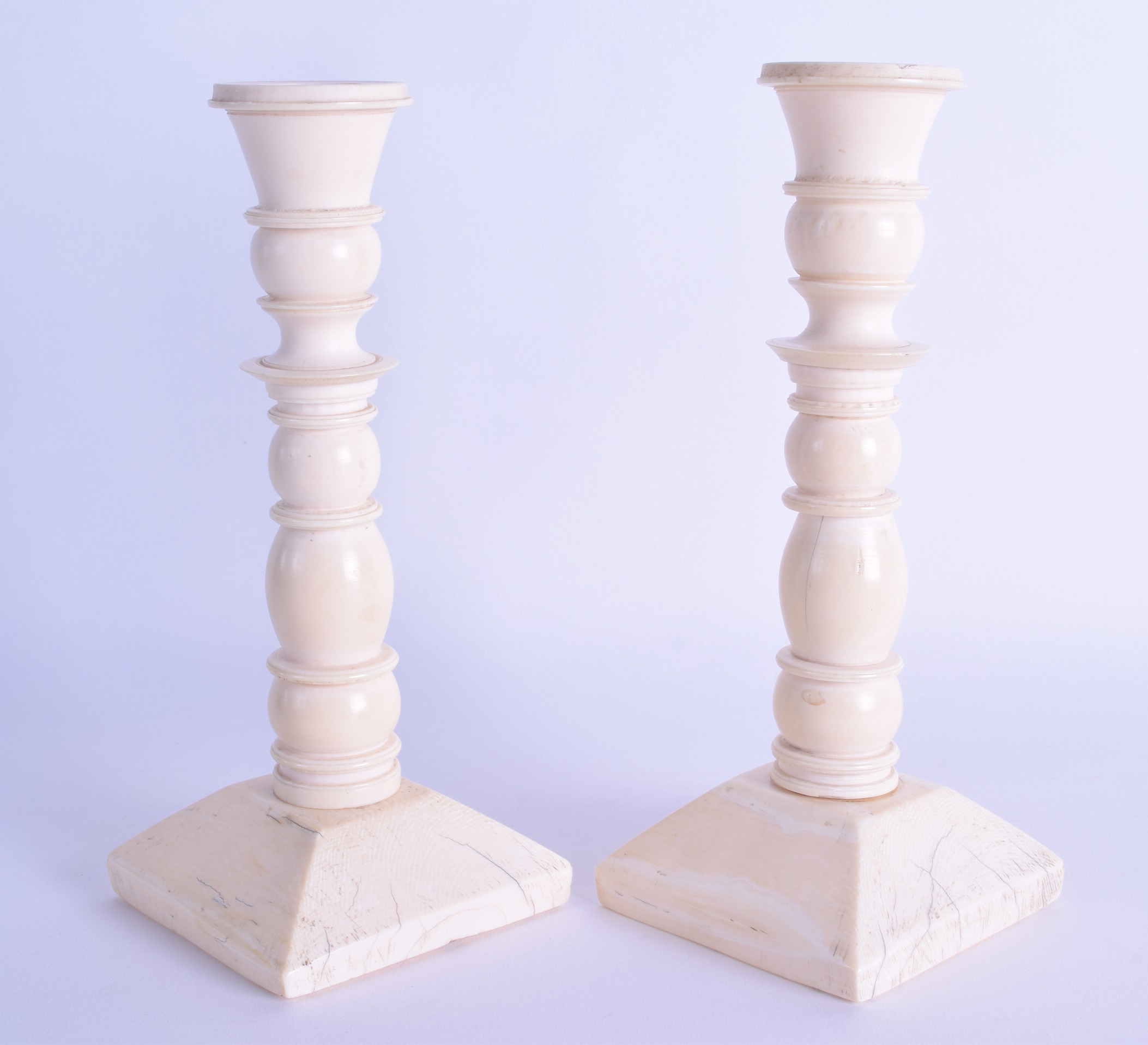 A GOOD PAIR OF MID 19TH CENTURY EUROPEAN CARVED IVORY CANDLESTICKS of ribbed form upon a square