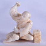 A 19TH CENTURY JAPANESE MEIJI PERIOD CARVED IVORY OKIMONO modelled as a male artisan forming a noh