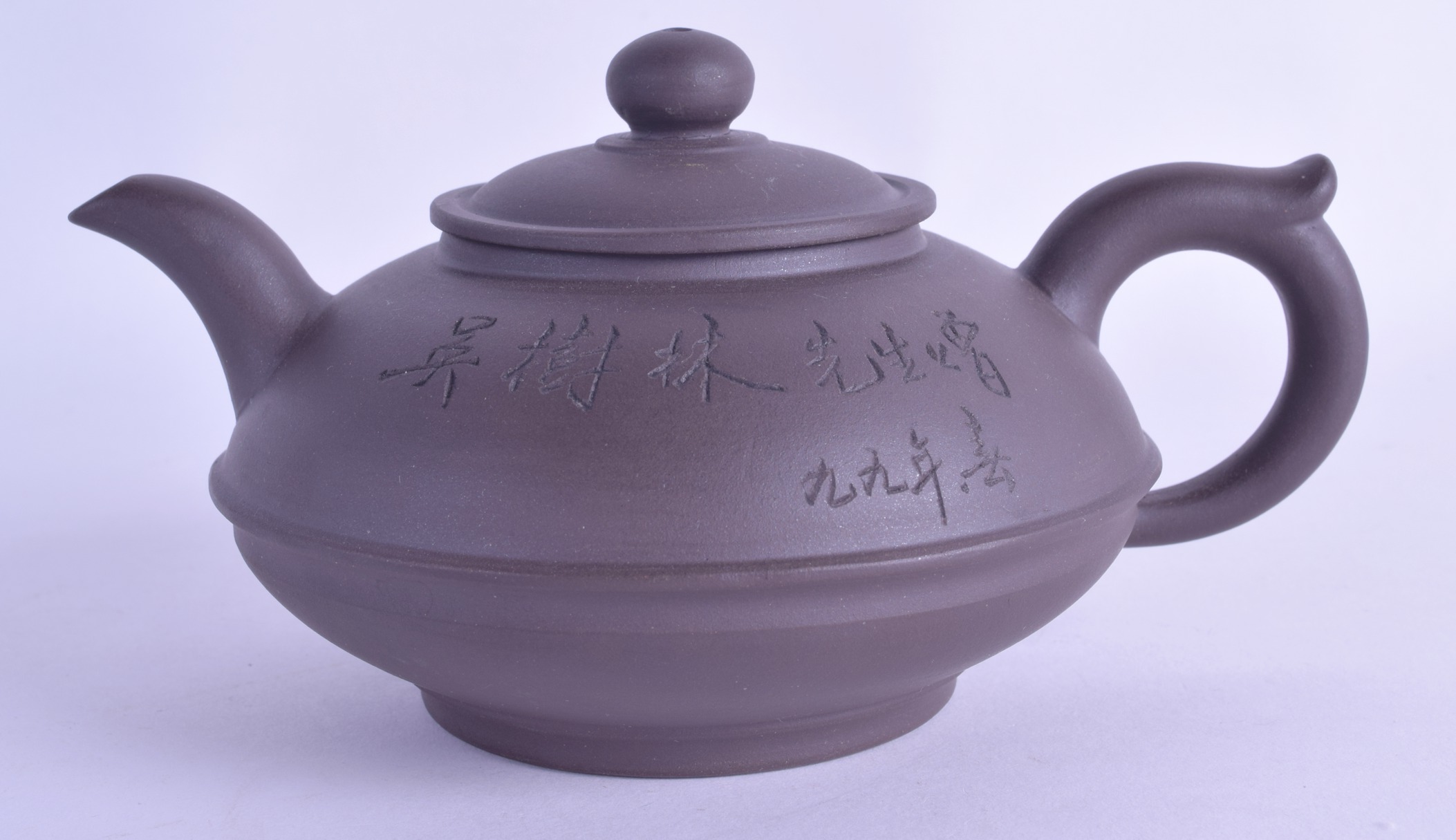 A CHINESE YIXING POTTERY TEAPOT AND COVER incised with calligraphy. 16 cm wide.