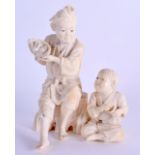 A 19TH CENTURY JAPANESE MEIJI PERIOD CARVED IVORY OKIMONO modelled as a male seated beside a young