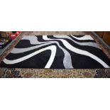 A STYLISH MODERN BLACK GROUND ABSTRACT RUG, decorated with waves of white and grey. 290 cm x 200