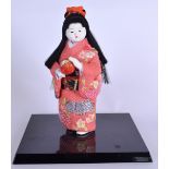A VINTAGE JAPANESE DOLL, modelled in a pink robe, mounted to a plinth. Figure 23 cm high.
