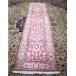 A PINK GROUND PERSIAN RUNNER, decortaed with flowering vines. 308 cm x 77 cm.