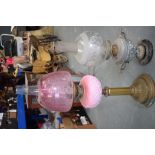 A VICTORIAN PINK GLASS OIL LAMP, together with another lamp. Largest 72 cm high.
