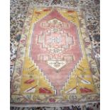 AN EARLY 20TH CENTURY SALMON PINK AND YELLOW GROUND OUSHAK RUG, decorated with geometric symbols.