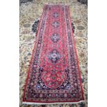 A 20TH CENTURY RED GROUND PERSIAN RUNNER, decorated with extensive foliage. 279 cm x 78 cm.