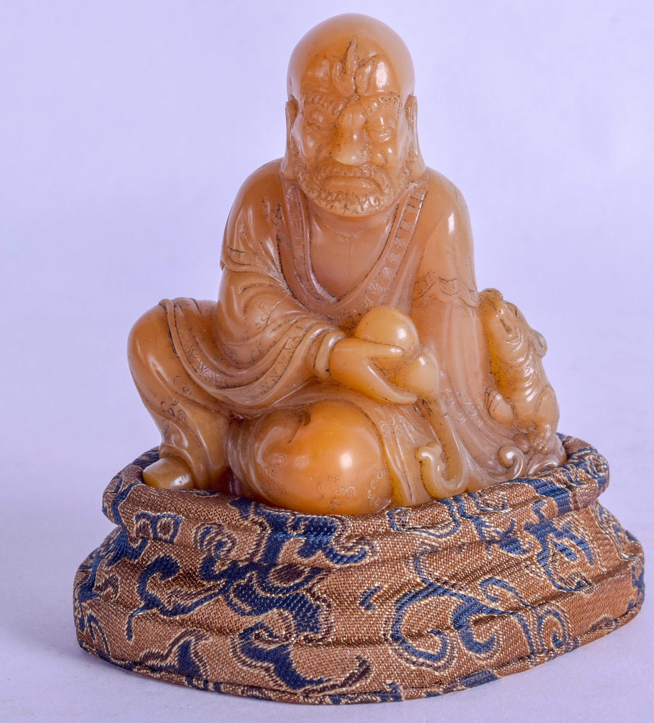 AN EARLY 20TH CENTURY CHINESE CARVED SOAPSTONE FIGURE OF A BUDDHA modelled beside a buddhistic