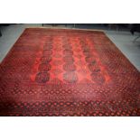 A LARGE EARLY 20TH CENTURY BURNT ORANGE GROUND AFGHAN ESARI TURKMEN RUG, decorated with motifs.