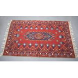 A RED GROUND WALL HANGING, decorated with motifs. 145 cm x 90 cm.