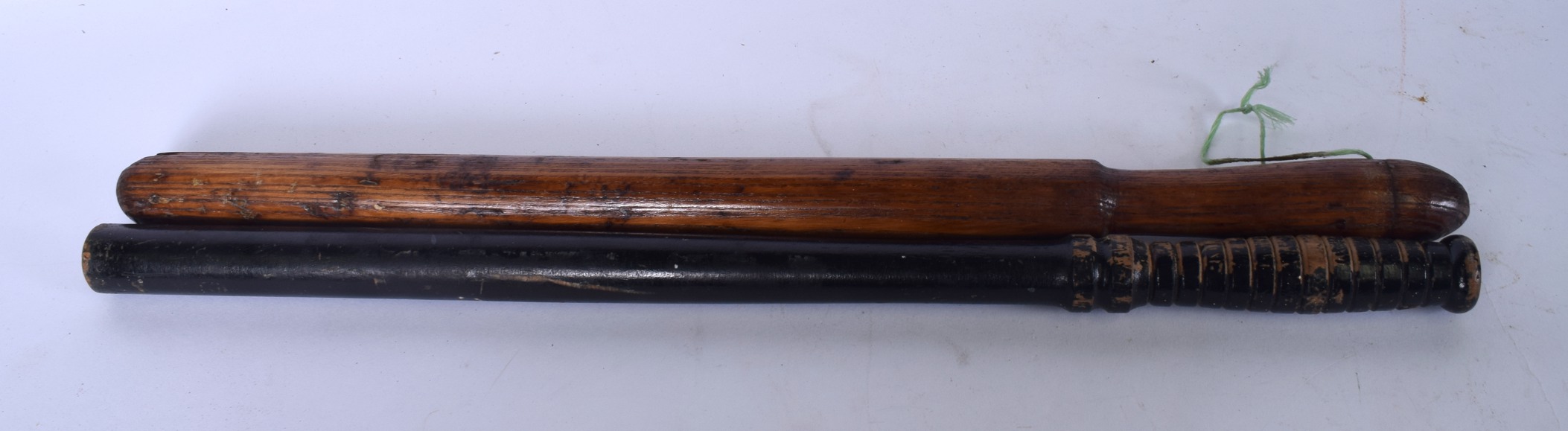 AN EARLY 20TH CENTURY WOODEN NIGHT STICK, together with a similar truncheon. Largest 56 cm .