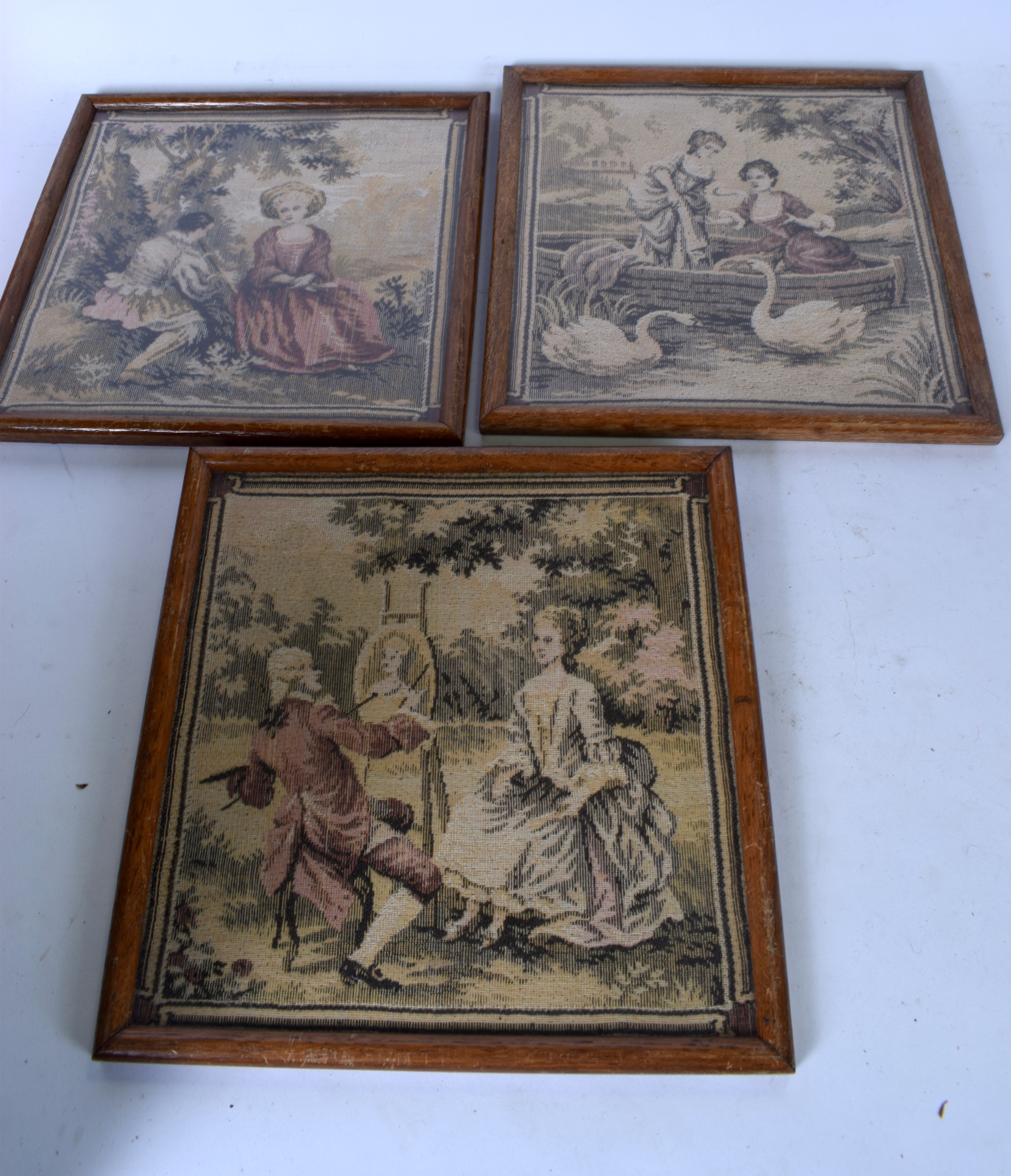 THREE EMBROIDERED PANELS, depicting figures in various pursuits. 24 cm x 23cm.