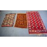 A RED GROUND PERSIAN RUG, together with two prayer mats. 140 cm x 74 cm. (3)