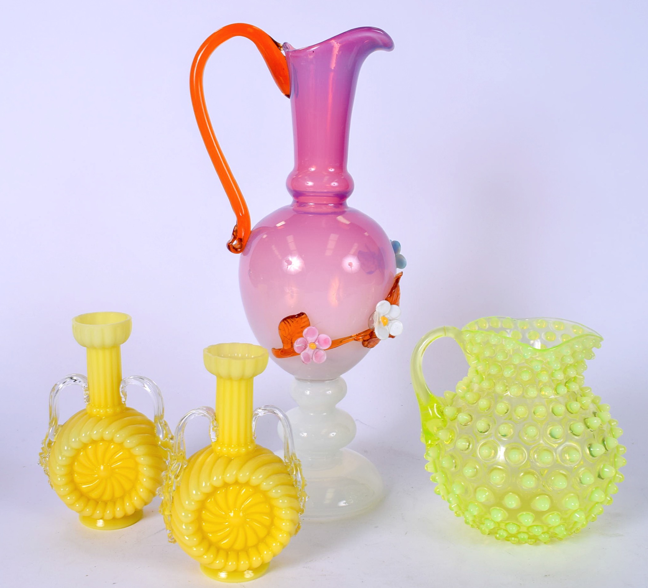 A PINK GLASS EWER OVERLAID WITH FLOWERS, together with a pair of vases and a jug. (4)
