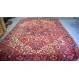 A LARGE RED GROUND RUG, decorated with foliage and symbols. 367 cm x 277 cm.