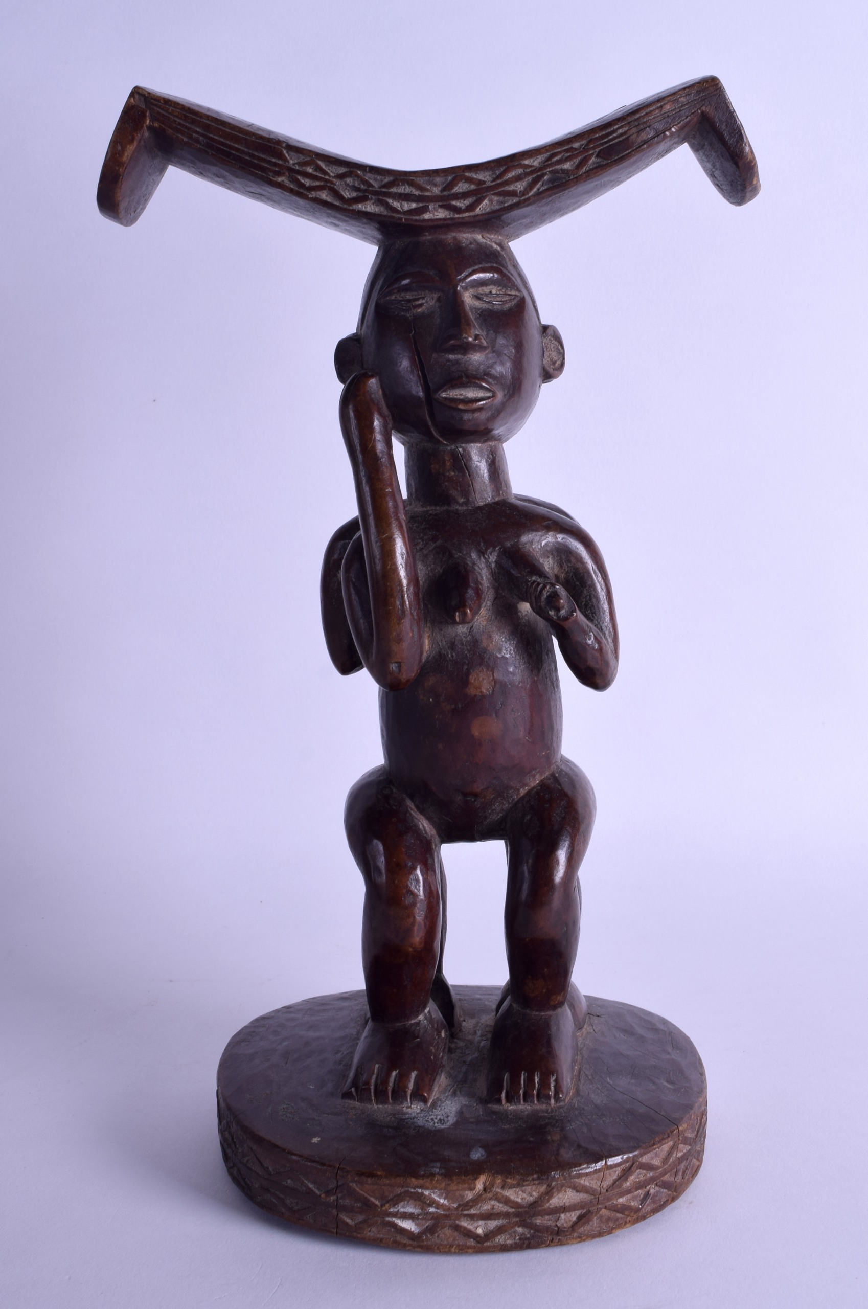 AN EARLY 20TH CENTURY AFRICAN TRIBAL HARDWOOD FERTILITY STOOL modelled as two opposing females