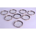 A SET OF EIGHT EARLY 20TH CENTURY SCOTTISH SILVER AND GLASS COASTERS with open work rims. 8 cm