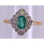 A STYLISH 18CT GOLD DIAMOND AND EMERALD FANCY RING the central emerald encased within fourteen 1/