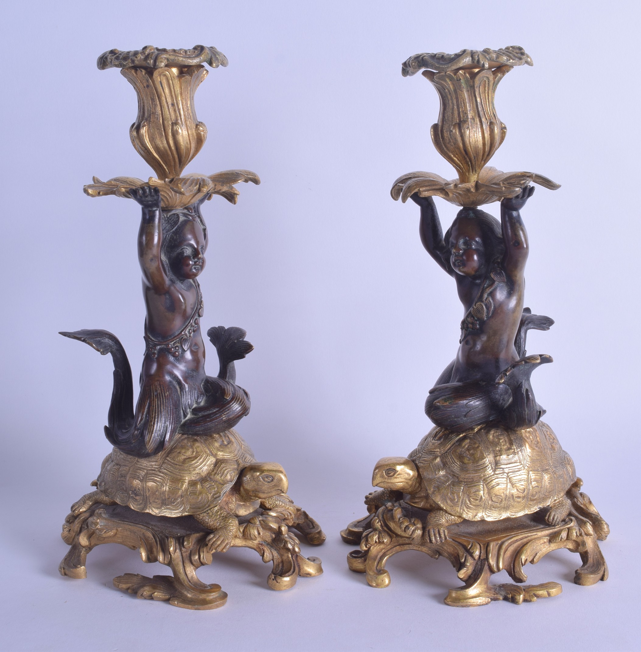 A PAIR OF MID 19TH CENTURY FRENCH BRONZE AND ORMOLU CANDLESTICKS modelled as putti resting upon