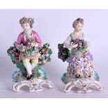 Derby pair of patch figures of a boy and girl seated on pierced rococo bases he holding flowers