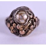AN ARTS AND CRAFTS MOTHER OF PEARL GOLD AND SILVER RING. Size F.
