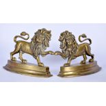 A PAIR OF CAST IRON DOORSTOPS IN THE FORM OF LIONS, modelled with one outstretched paw. 23 cm wide.