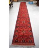 A LONG KHAL MOHAMMADI RED GROUND RUG RUNNER, decorated with panels of foliage. 551 cm x 76 cm.