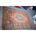 AN ORANGE GROUND PERSIAN RUG, decorated with foliage. 187 cm x 125 cm.