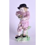 Derby figure of a boy wearing a large black hat holding a handled pot of food. 13cm high