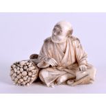 A 19TH CENTURY JAPANESE MEIJI PERIOD CARVED IVORY OKIMONO modelled as a seated male beside chopped