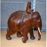 A CARVED INDIAN SCULPTURE IN THE FORM OF AN ELEPHANT, carved with a seated male rider. 26 cm wide.