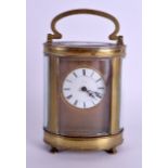 AN EARLY 20TH CENTURY FRENCH BRASS OVAL CARRIAGE CLOCK with unusual circular enamelled dial