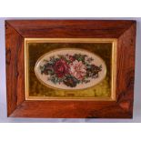 AN EARLY 20TH CENTURY NEEDLEPOINT DEPICTING FLOWERS, held in a rosewood frame and velvet mounts.
